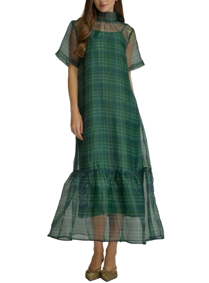 A woman models a green plaid midi dress with sheer short sleeves, a high mock neck, and a tiered ruffled hem, set against a plain gray studio background.
