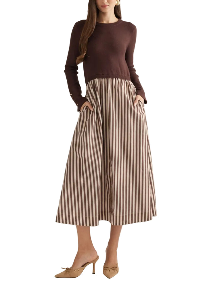 A woman modeling a dark brown long-sleeve knit top paired with high-waisted, wide-leg pleated trousers featuring brown and beige vertical stripes, styled with beige pointed-toe heels against a solid light beige studio background.