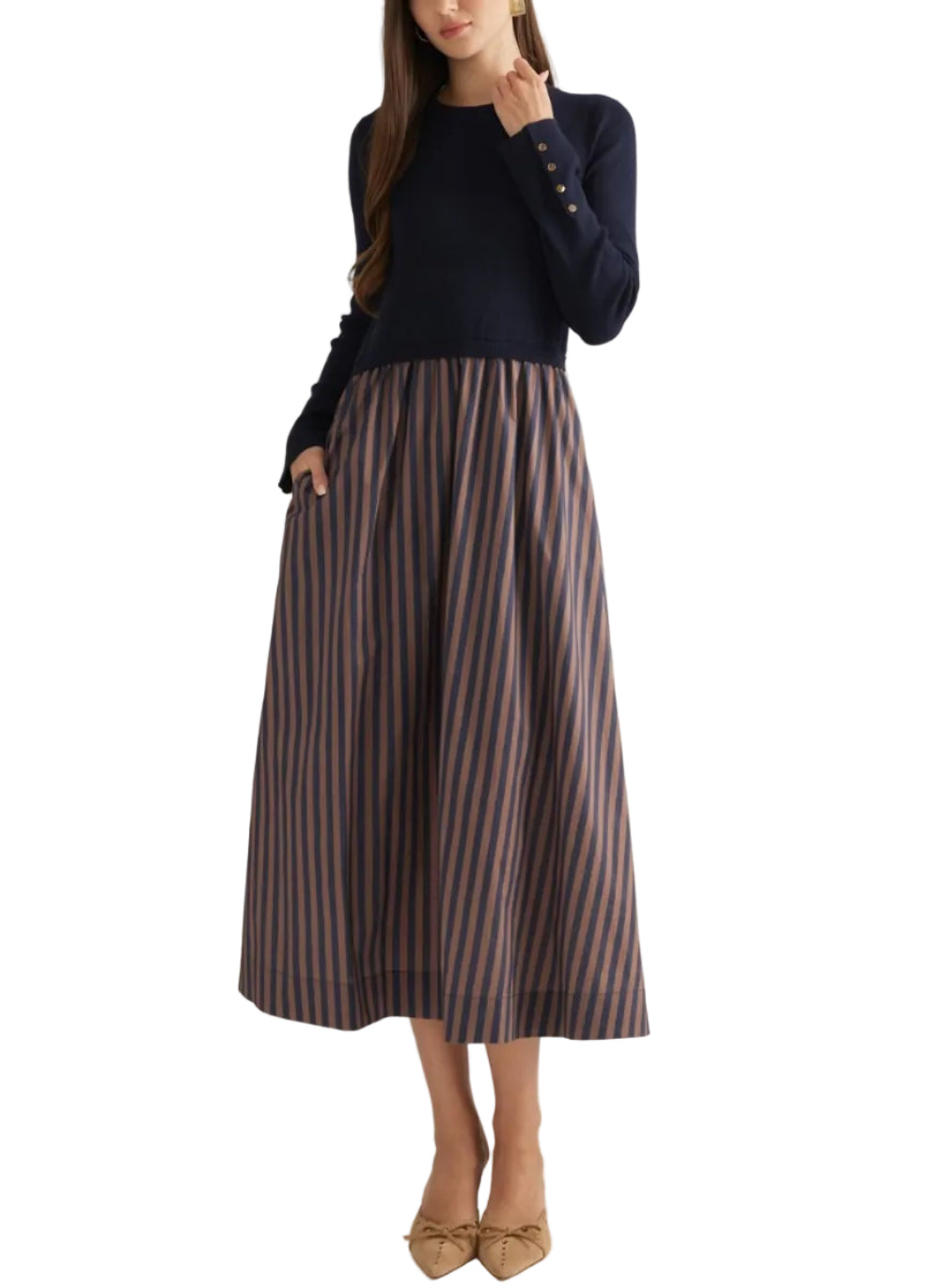 A woman modeling a dark navy long-sleeve knit top paired with a high-waisted midi skirt featuring vertical navy and rust-orange stripes, set against a plain light beige studio background.