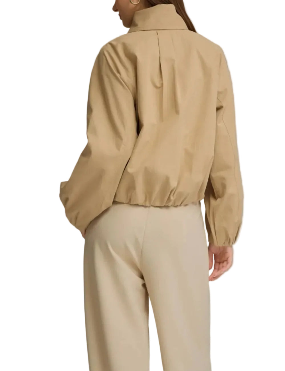 A woman shown from the back wearing a beige cropped jacket with a high collar and long sleeves, paired with light beige trousers, against a solid gray studio background.