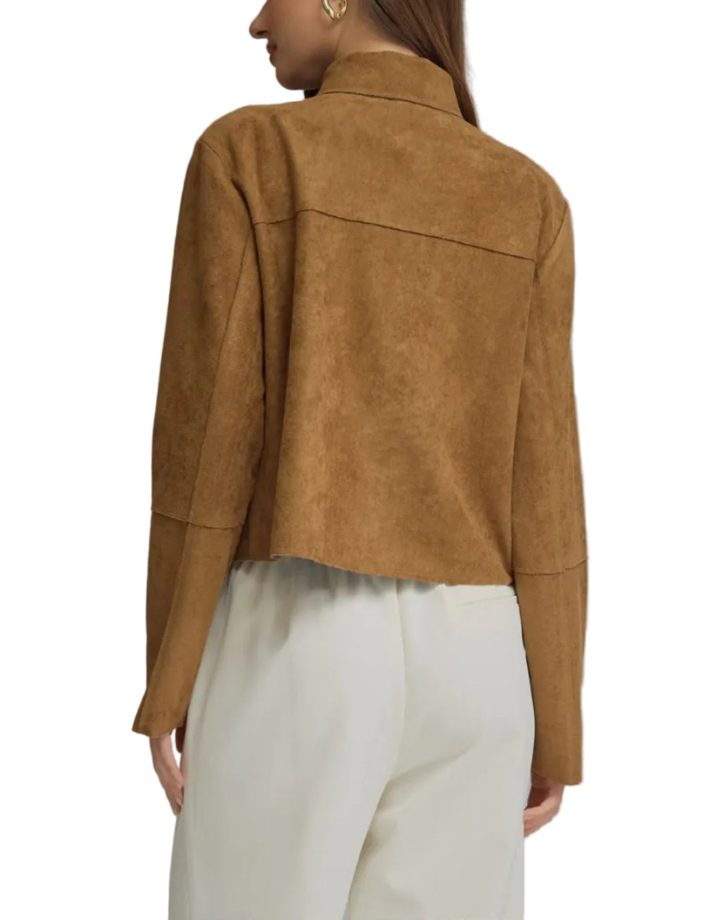 A woman shown from the back wearing a cropped tan suede jacket and white trousers against a plain gray studio background.