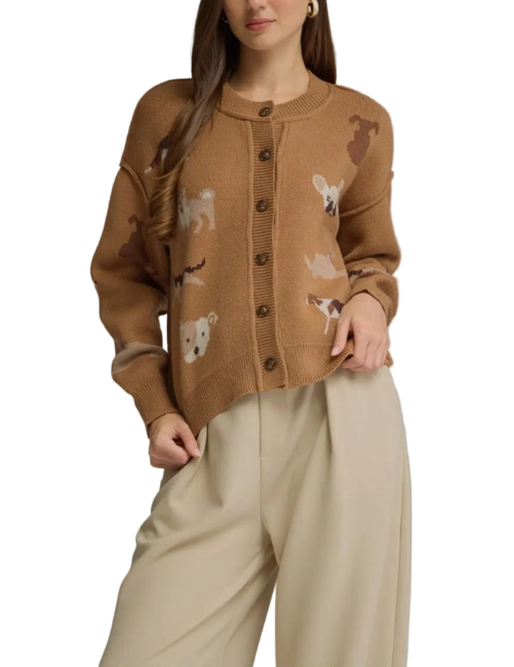 A woman modeling a cropped brown knit cardigan with dog illustrations, paired with beige wide-leg pants, against a solid gray studio background.