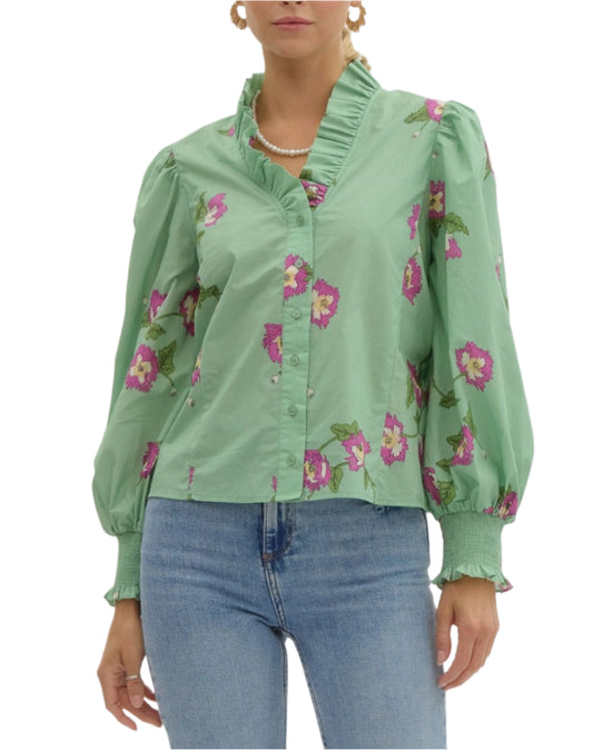 Printed button front smocked cuff long sleeve top featuring v-neck with accented with voluminous ruffle. Unlined. Woven. Non-sheer. Lightweight.