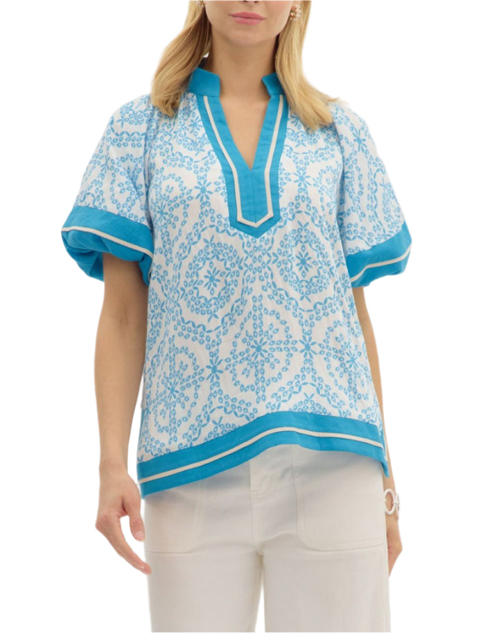 Morracan print short bubble sleeve pullover top featuring contrast caftan-inspired structured neck band. Contrast accent outline slit hem. Unlined. Woven. Non-sheer. Lightweight.