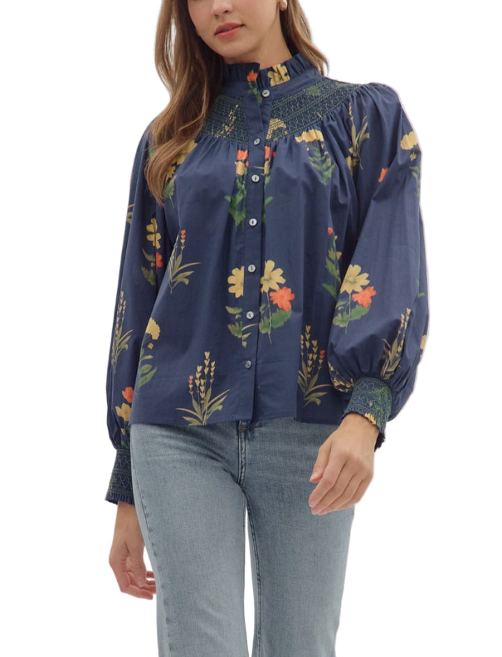 Floral print long sleeve top featuring smocked yoke and ruffled mock neck. Button closure at front. Smocked cuffs. Unlined. Woven. Non-sheer. Lightweight.
