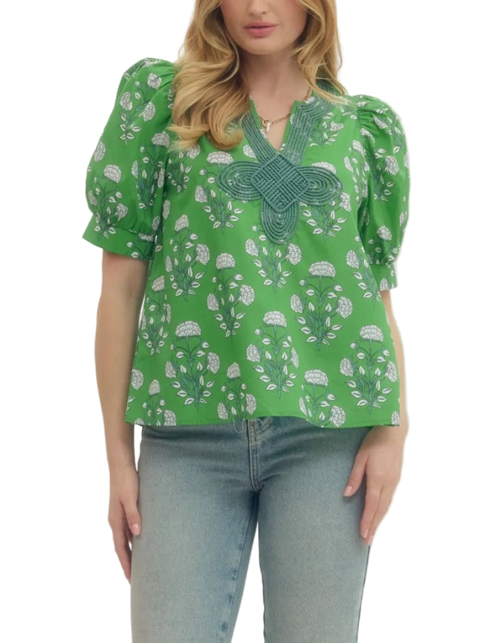 Floral print puff short sleeve top featuring V-neck with knotted applique detail. Unlined. Woven. Non-sheer. Lightweight.
