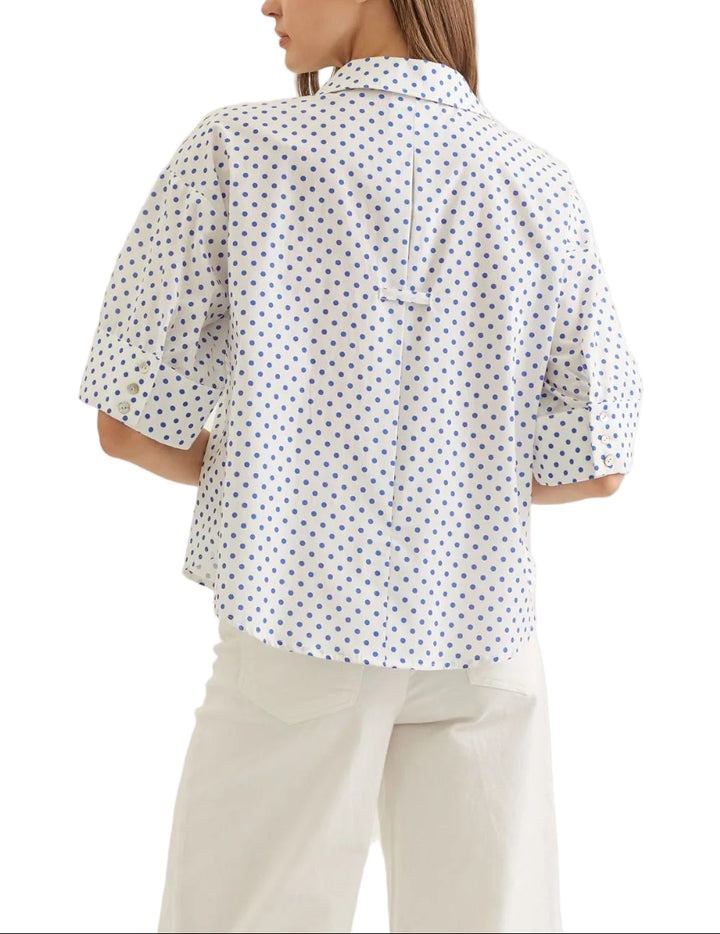 Polka dot short sleeve top featuring cuff button detail. Collar neckline. Split V-neck. Back tab detail. Unlined. Woven. Non-sheer. Lightweight.