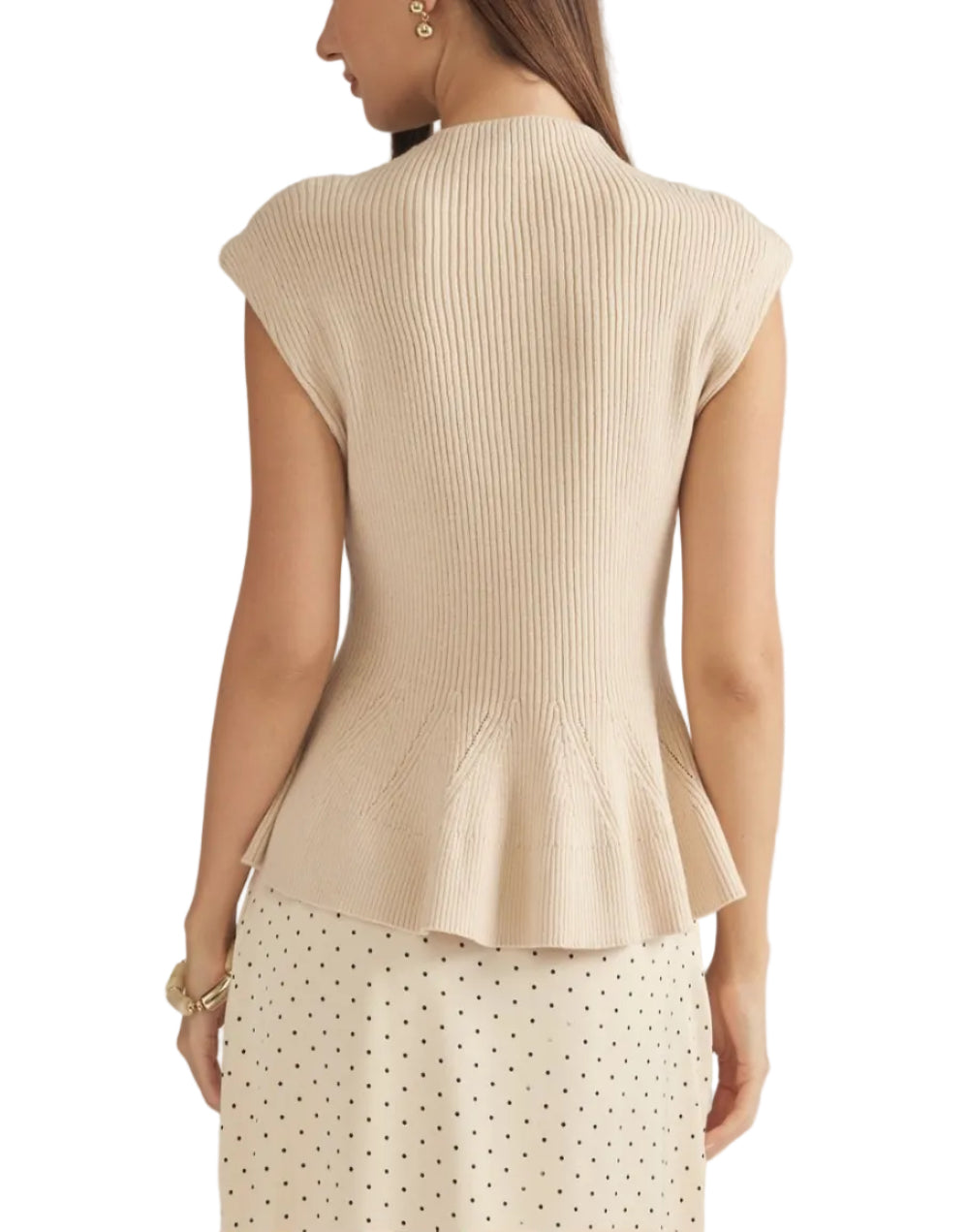 A woman shown from the back wearing a cream ribbed knit peplum top and a matching cream polka dot skirt against a light gray studio background.