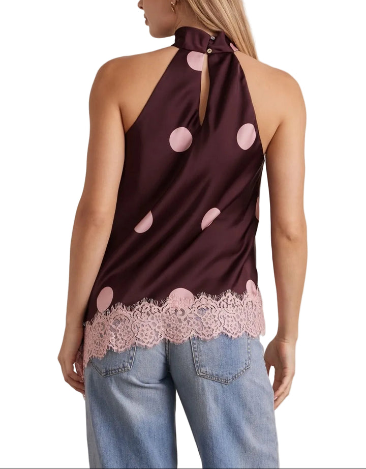 The Beau Polka Dot Halter Top combines playful style with elegant details. Classic polka dots create a timeless look, while delicate lace trim adds a touch of sophistication. The asymmetrical hem brings modern movement and visual interest to this versatile piece. Perfect for casual outings or dressed up for special occasions, this halter top offers a flattering silhouette with contemporary flair.