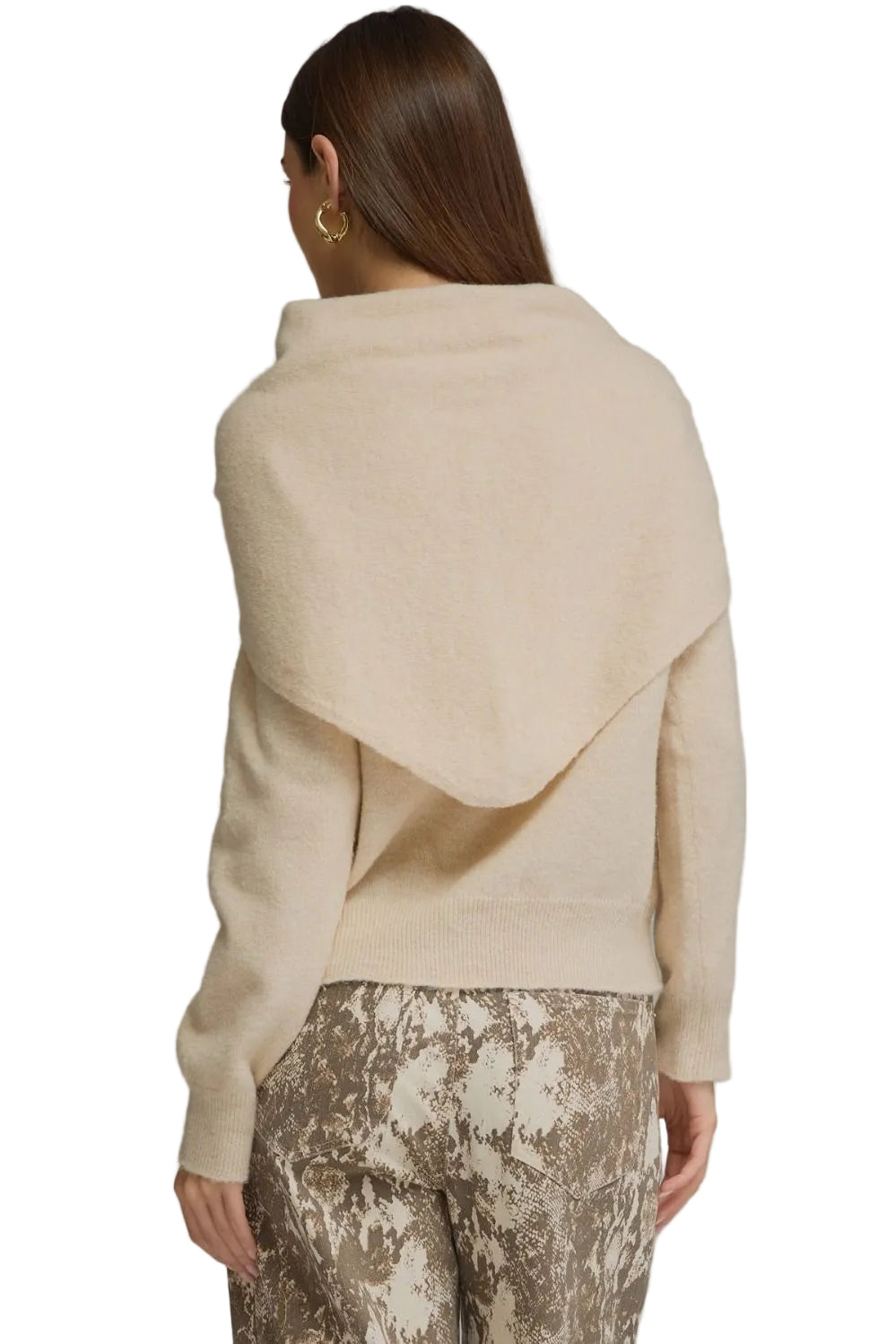 A woman shown from the back wearing a cream-colored knit wrap sweater and patterned pants against a neutral gray studio background.