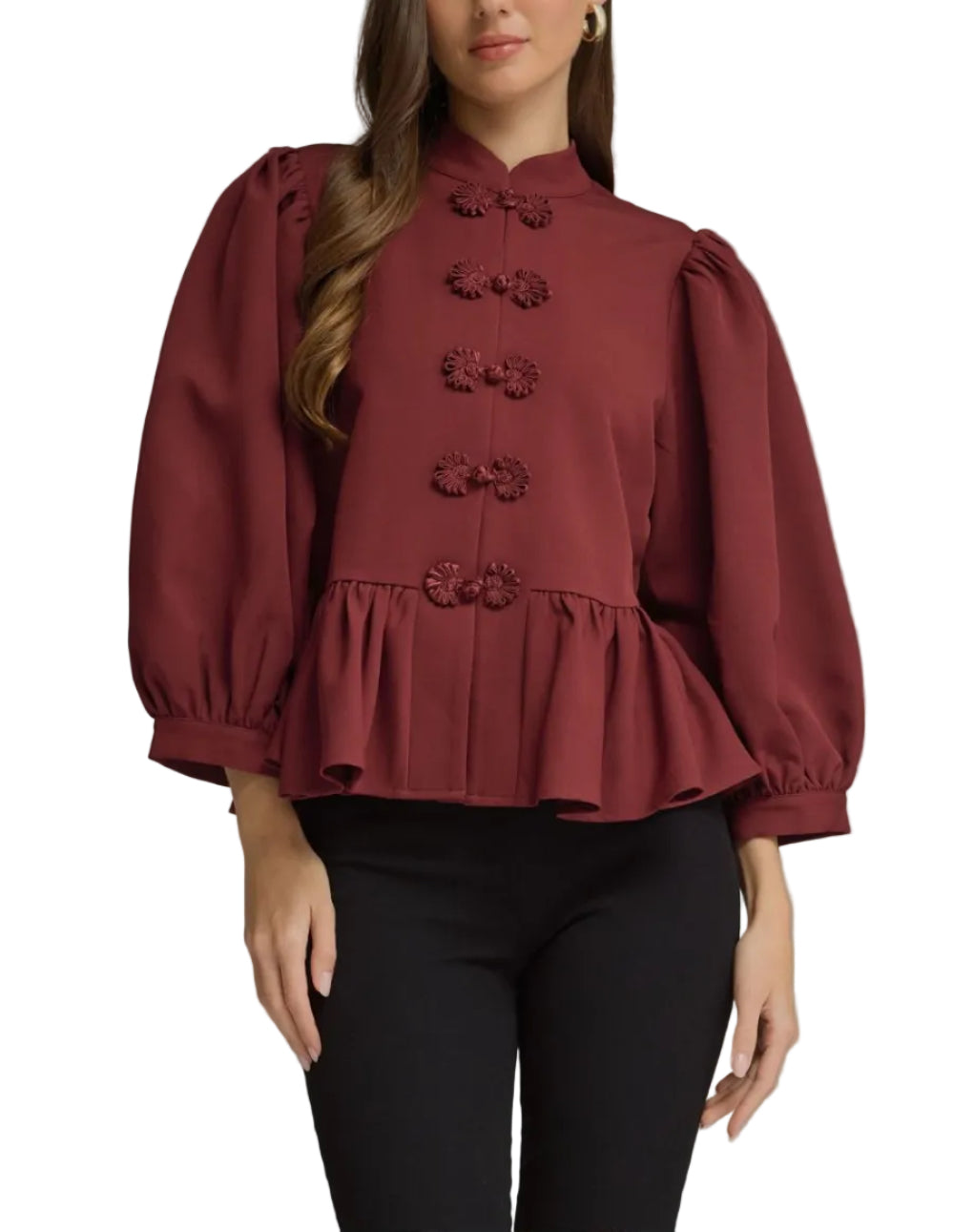 A woman modeling a burgundy long-sleeve blouse with puff sleeves, a high collar, and decorative button details, paired with black pants against a neutral gray studio background.