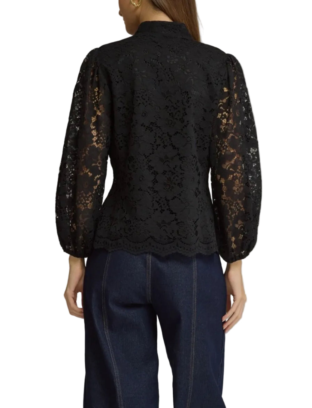 A woman shown from the back wearing a black lace long-sleeve blouse with sheer lace sleeves and dark blue jeans, photographed against a plain gray studio background.