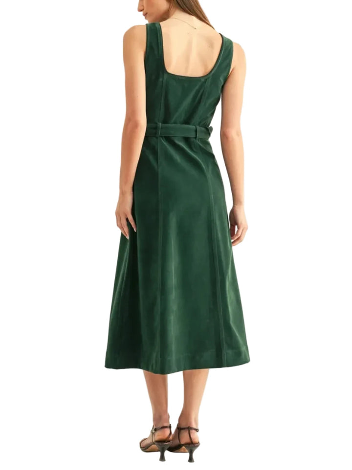 A woman modeling a dark green sleeveless midi dress with a tie waist belt, shown from the back against a plain off-white studio background.