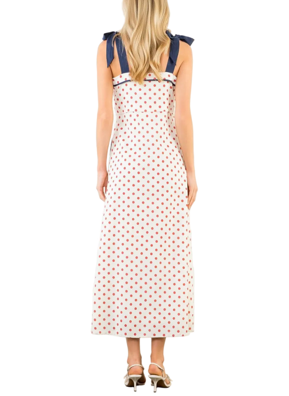 Woman wearing a polka dot dress with blue straps on a white background