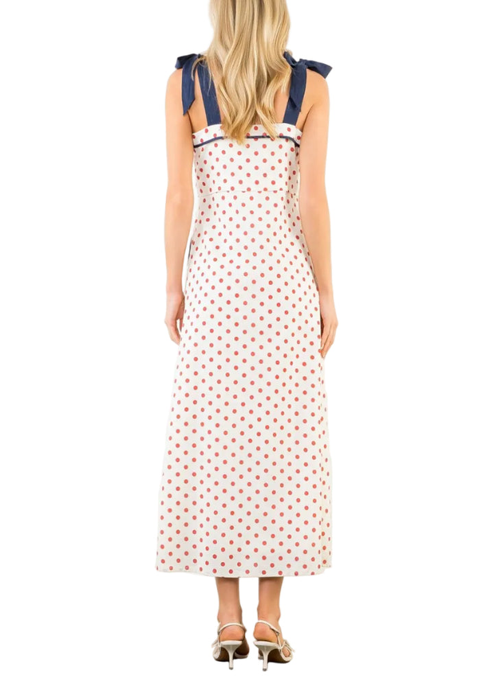 Woman wearing a polka dot dress with blue straps on a white background
