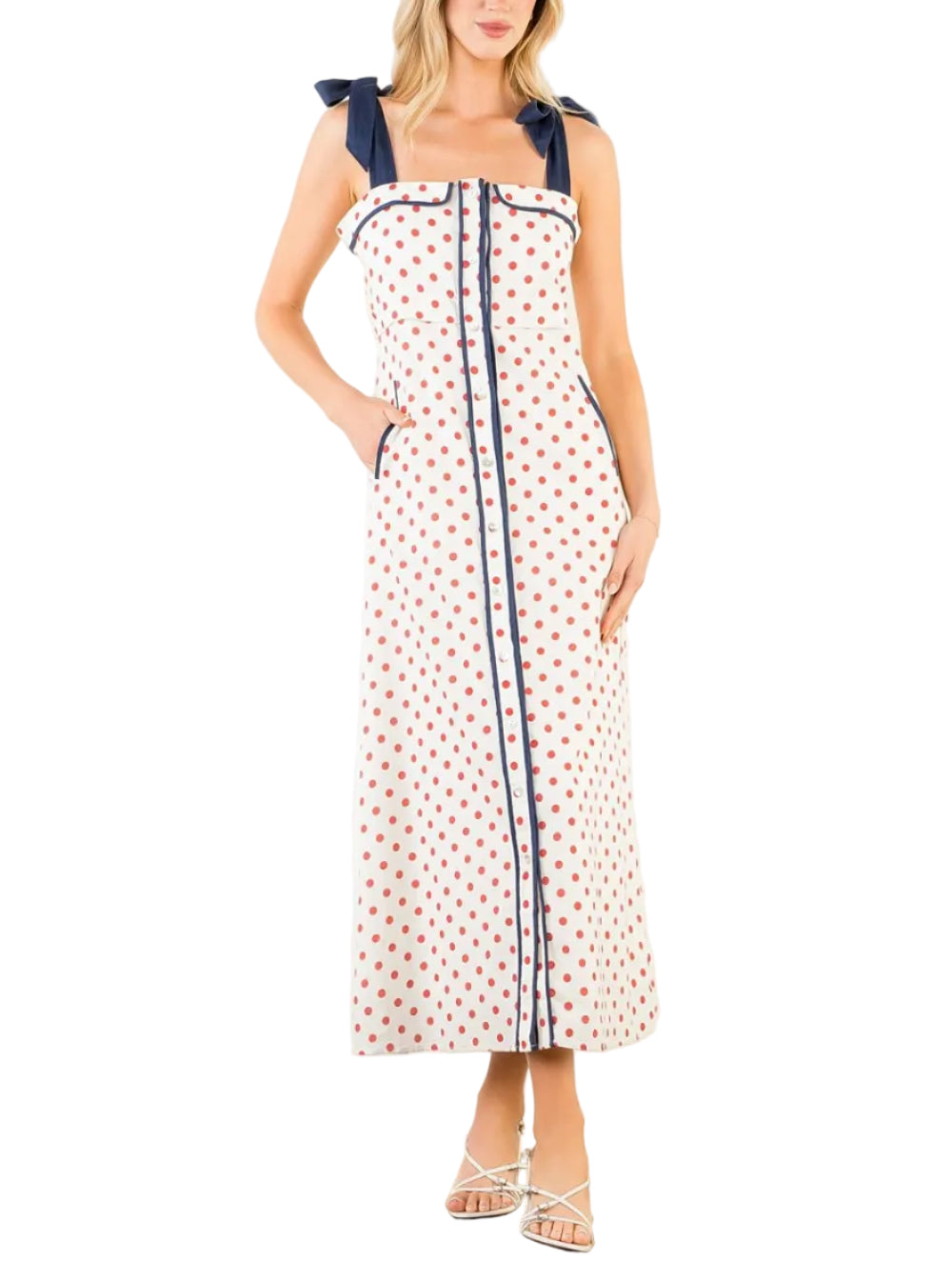 Woman wearing a white dress with red polka dots and blue straps on a white background