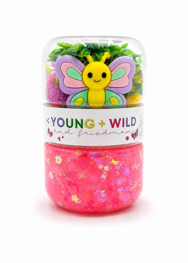 A clear plastic jar filled with bright pink glitter slime on the bottom half and a colorful butterfly-shaped charm with green, purple, and yellow wings on the top half. A white label around the middle reads &