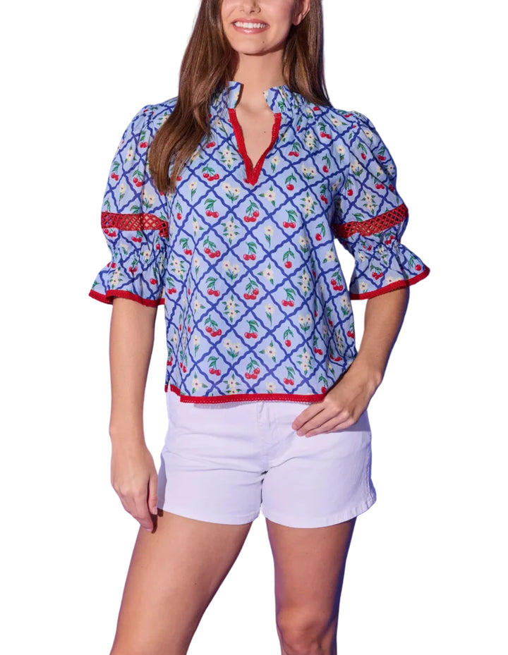 The Lottie Top brings a fun and flirty energy to the beloved cherry lattice print. Voluminous puff sleeves gather into ruffled cuffs accented with red crochet trim — the same playful detail that frames the split V-neckline and hem. The relaxed, easy-to-wear silhouette pairs effortlessly with white shorts or denim for a summer look that&