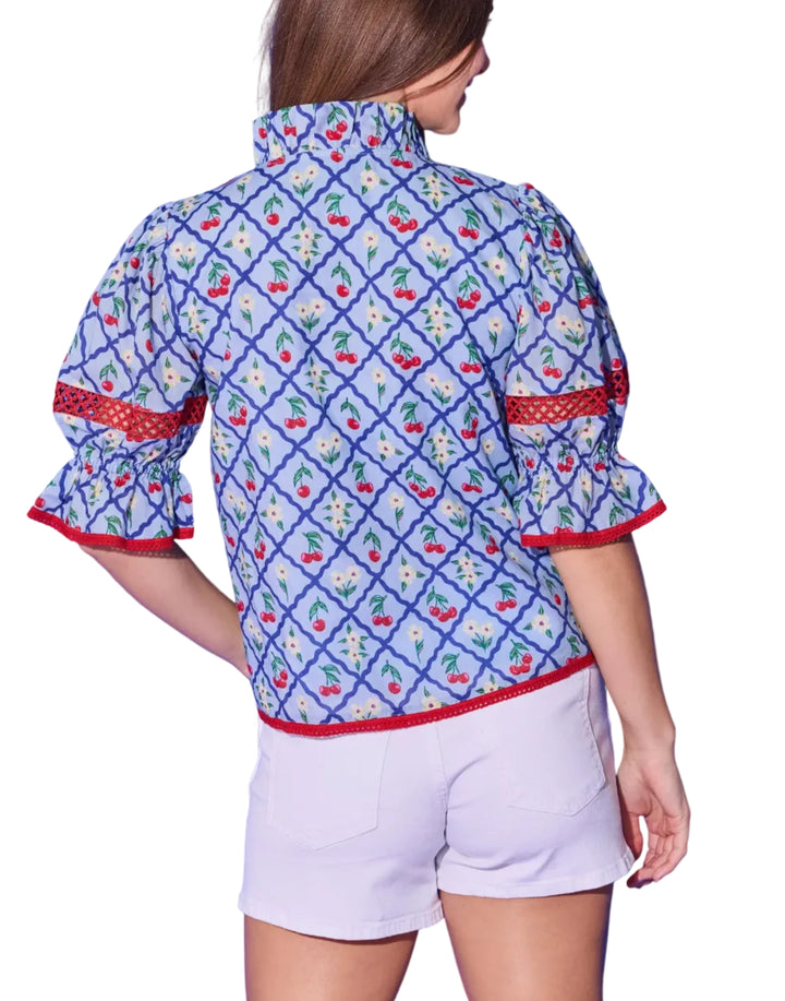 The Lottie Top brings a fun and flirty energy to the beloved cherry lattice print. Voluminous puff sleeves gather into ruffled cuffs accented with red crochet trim — the same playful detail that frames the split V-neckline and hem. The relaxed, easy-to-wear silhouette pairs effortlessly with white shorts or denim for a summer look that&