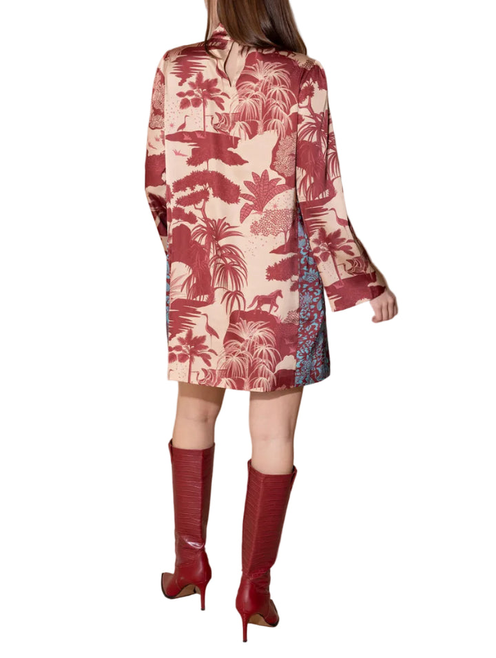 A woman is shown from behind wearing a vintage-style long-sleeve shirt dress with a red and beige tropical palm tree print, paired with matching red knee-high boots, against a solid beige studio background.