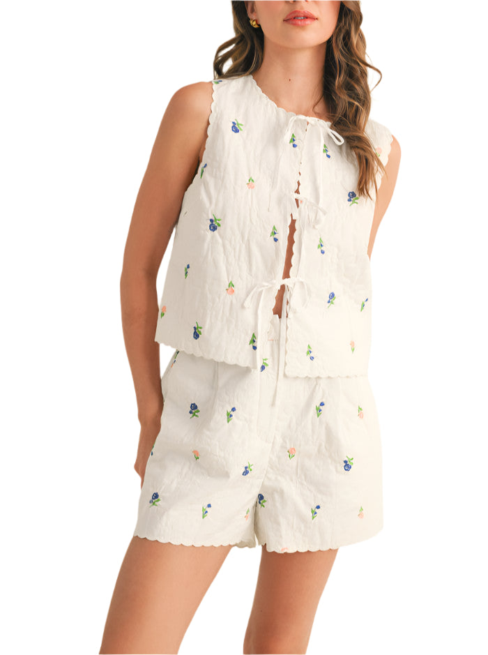 Step out looking cute and coordinated in this quilted vest and shorts set! Lightweight quilted fabric, with floral embroidery throughout, shapes a relaxed vest top with a scalloped round neckline and open front with bow tying closure. Matching shorts feature a high pleated waistband with zipper and button closure, pockets, and scalloped hem. Pair this set with sneakers or sandals for a trendy coordinated look!