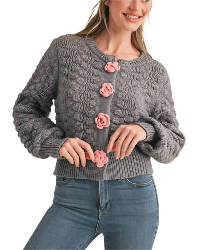 textured sweater knit that shapes a button front design with knit rosettes and a relaxed fit framed by long sleeves with ribbed cuffs.