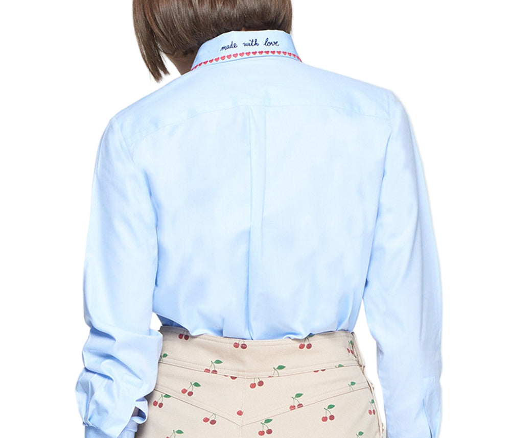 Classic-fit light blue shirt with a pointed collar embroidered with a line of red hearts. Red “Don’t overthink it” text embroidered on the cuff and a “Made with love” message on the back of the collar in black thread. Front closure with visible buttons. Curved hem. Structured yet light poplin fabric.