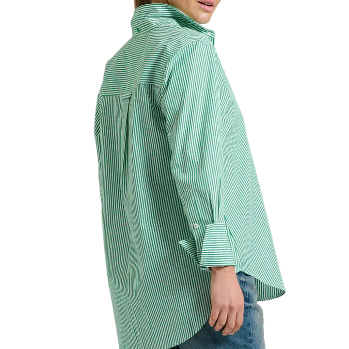 Woman wearing a green checkered shirt and blue jeans on a light gray background