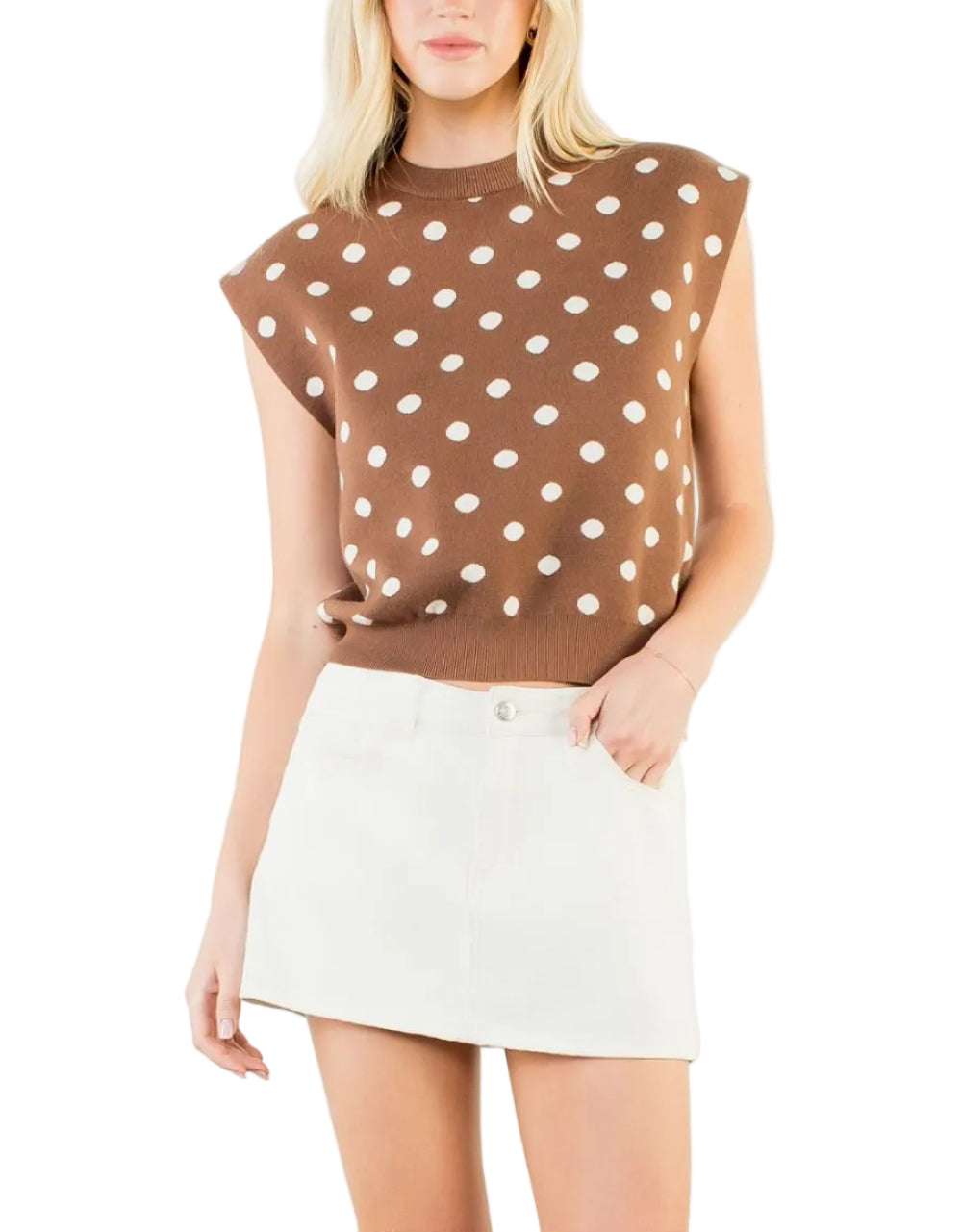 Woman wearing a brown sleeveless top with white polka dots and a white skirt on a white background